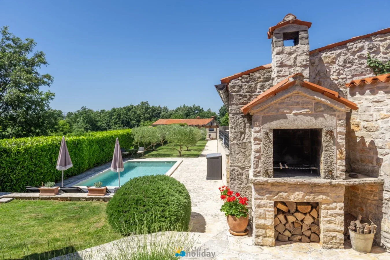 Stone outdoor fireplace beside garden swimming pool