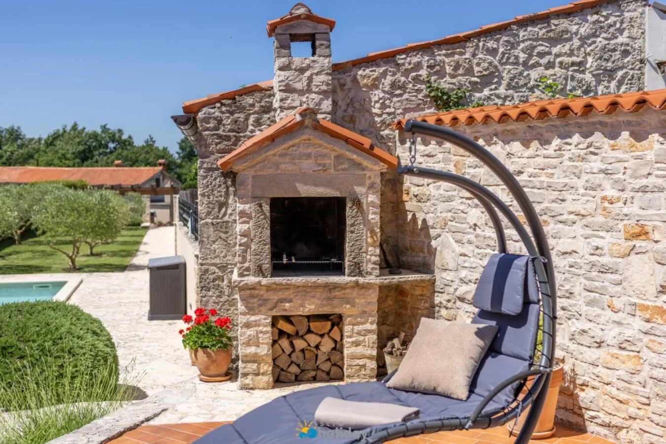 Stone outdoor fireplace beside lounge chair and pool