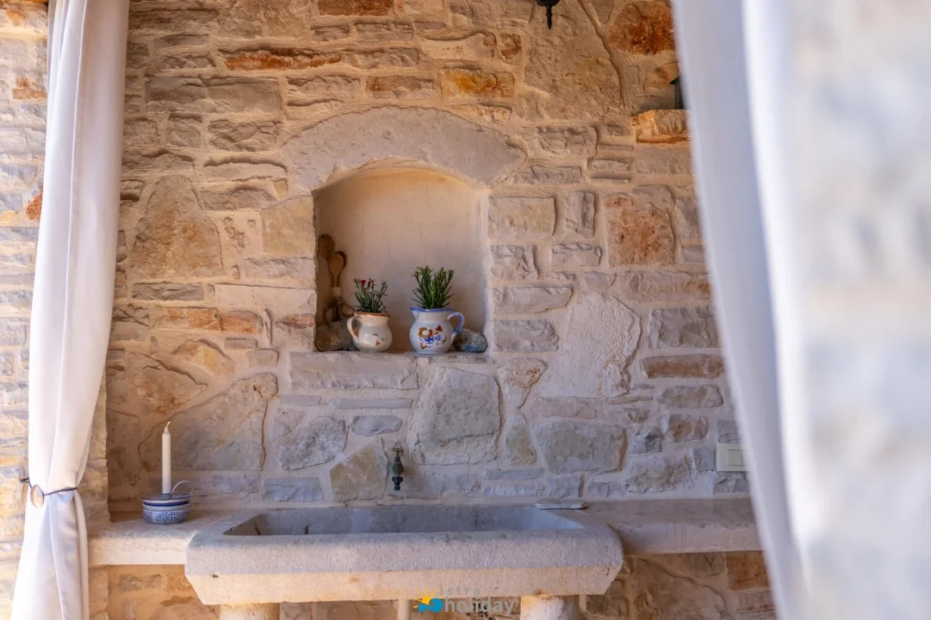 Rustic stone sink with potted plants and candle