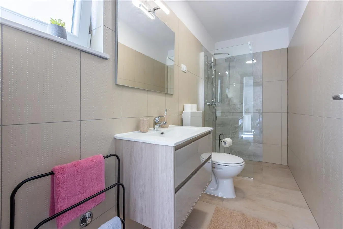 Modern beige bathroom with glass shower and vanity