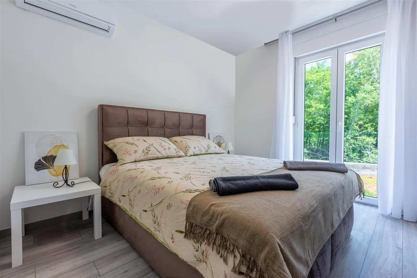 Bright modern bedroom with balcony and greenery view