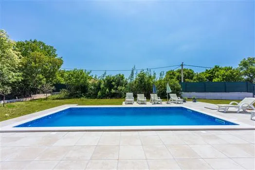 Modern backyard swimming pool with lounge chairs