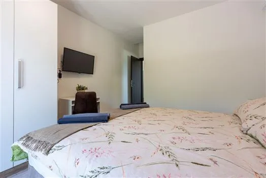 Modern bedroom with floral bedding and wall-mounted TV