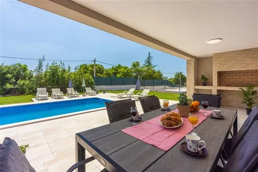 Covered patio dining area overlooking backyard pool