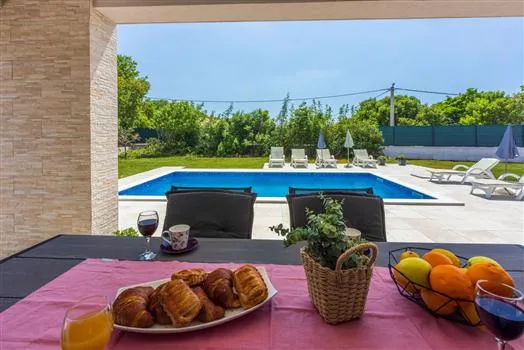 Breakfast table overlooking backyard pool and lounge chairs