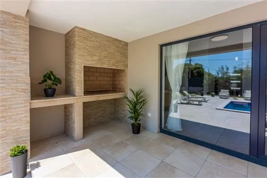 Modern patio with built-in grill and pool view