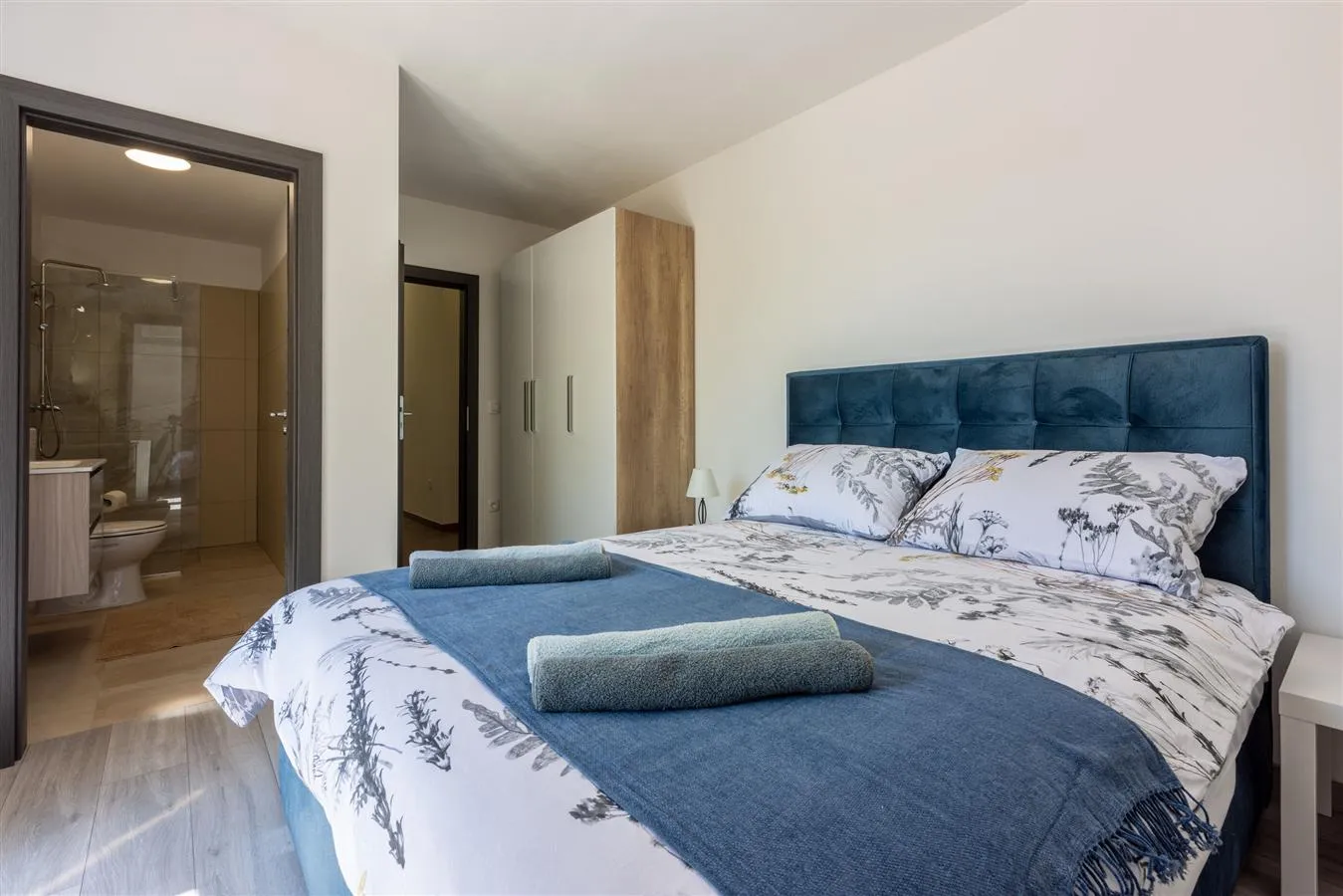 Modern bedroom with blue headboard and ensuite bathroom
