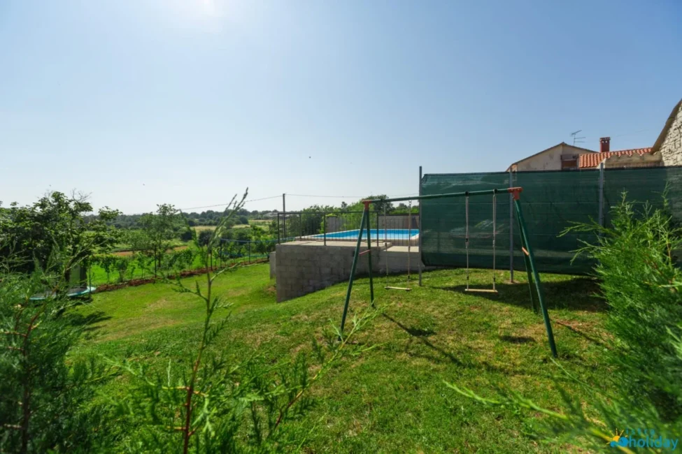Backyard with pool and swings under clear sky.