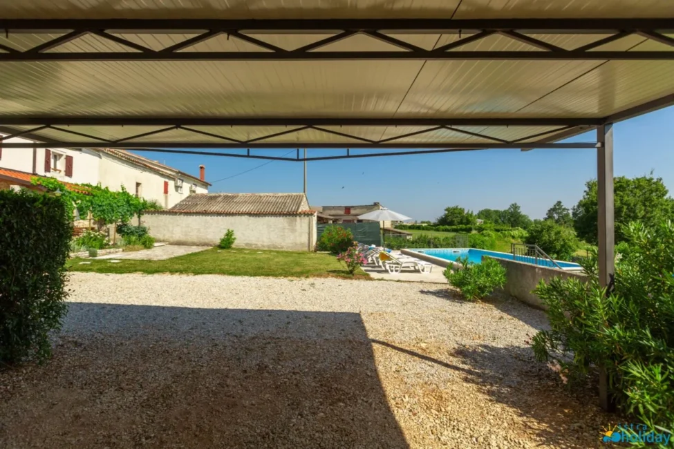 Covered patio with view of pool and garden.