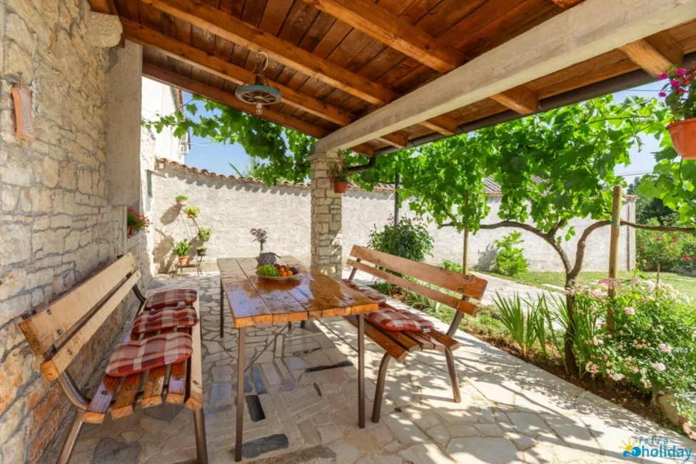 Rustic patio with wooden furniture and greenery.