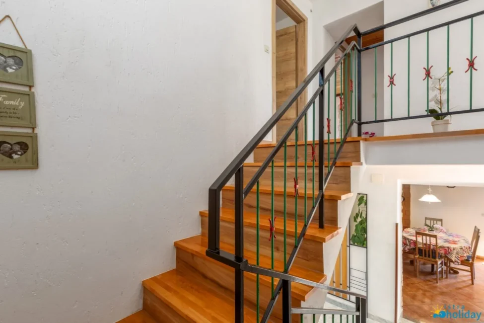 Wooden staircase with metal railing and dining area.