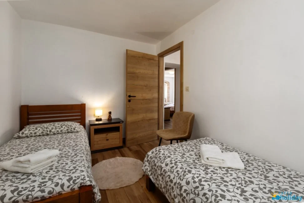 Cozy bedroom with two single beds and lamp.