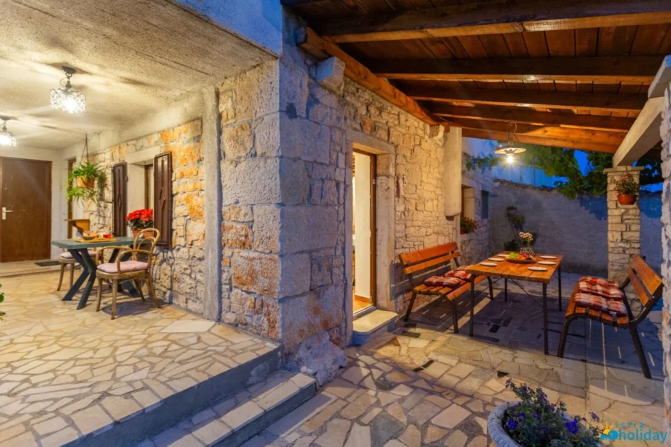 Charming stone patio with dining area and lights.