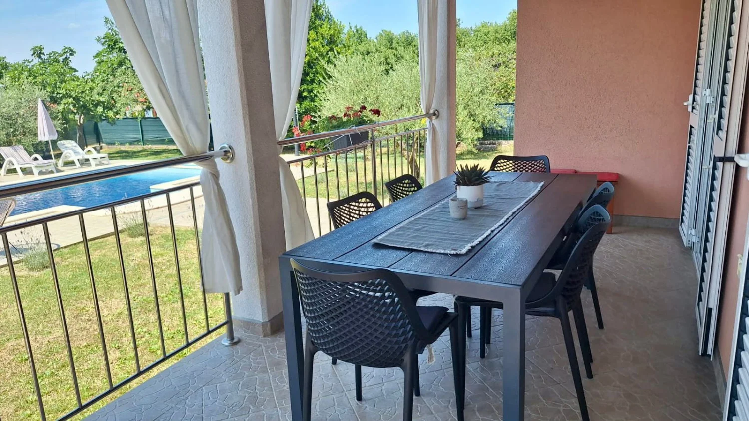 Covered patio dining area overlooking pool and garden