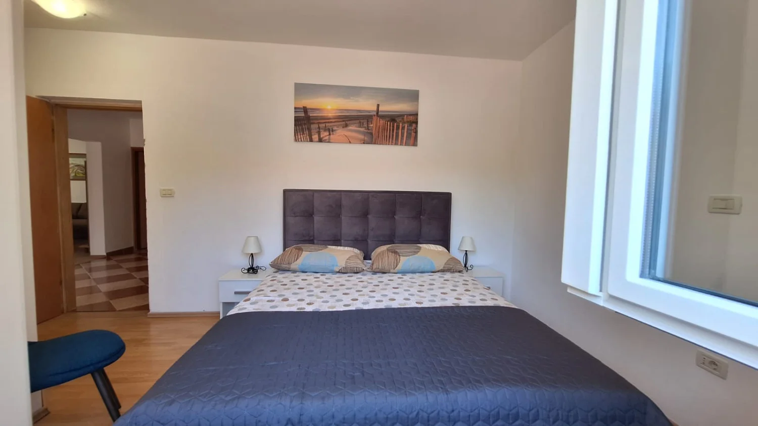 Modern bedroom with double bed and beach artwork