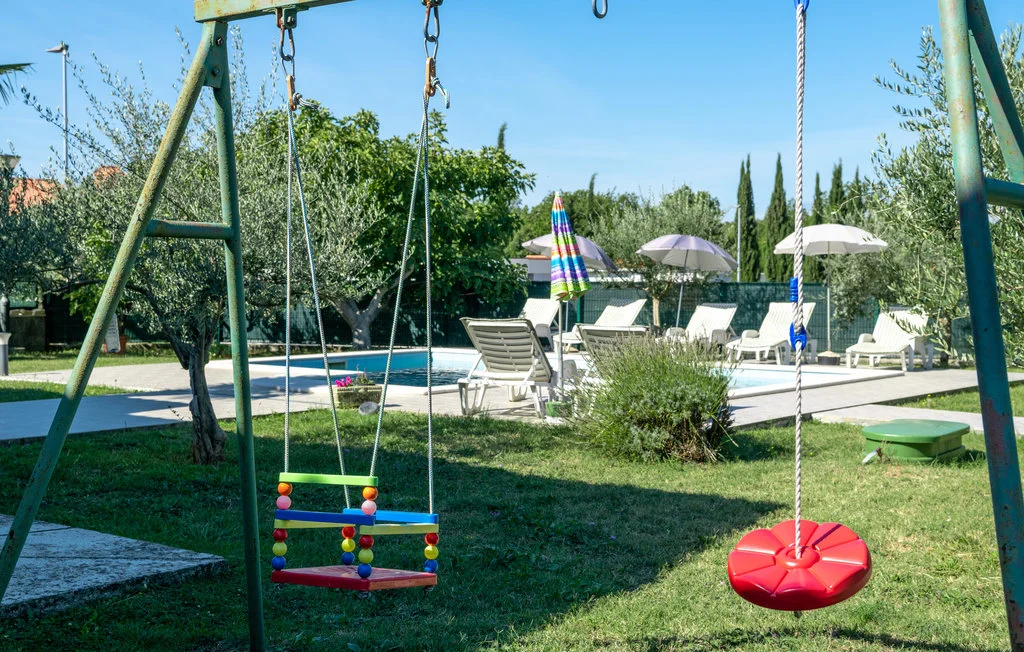 Backyard swings near pool and lounge chairs