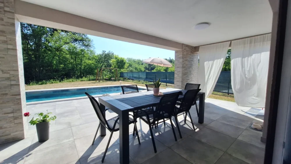 Covered patio with dining table overlooking swimming pool