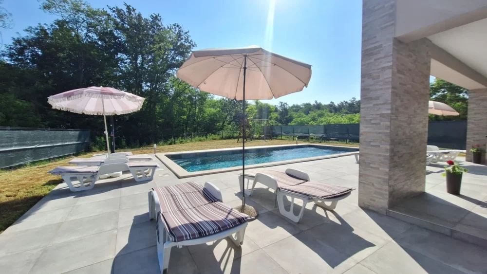 Modern backyard pool with lounge chairs and umbrellas