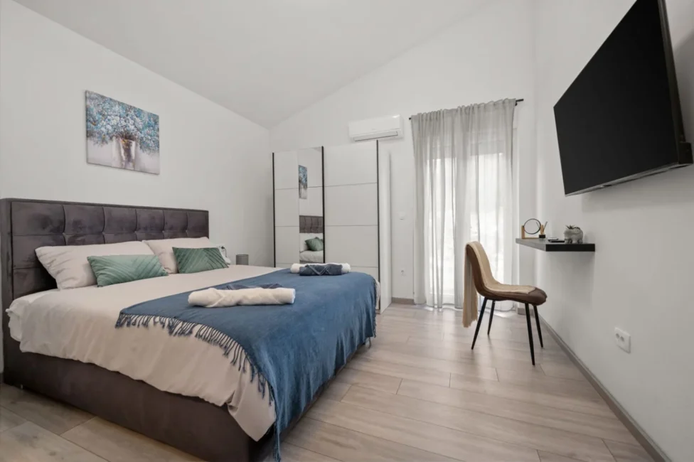 Modern minimalist bedroom with blue accents and TV