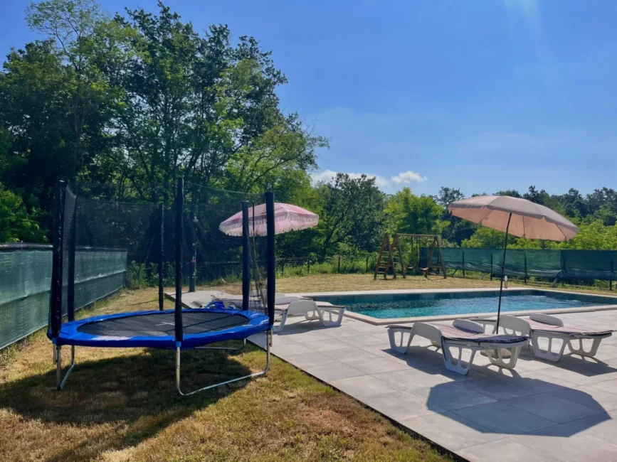 Backyard pool with lounge chairs and trampoline