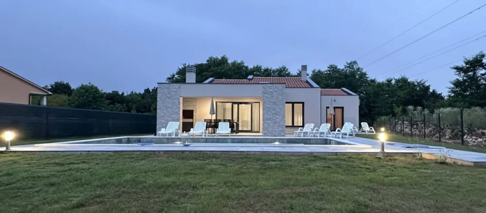 Modern single-story home with pool at dusk